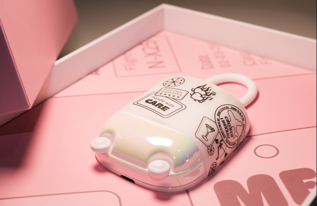 The NOX Traveller suitcase-style charging case with luggage-tag stickers, packed inside its pink gift box