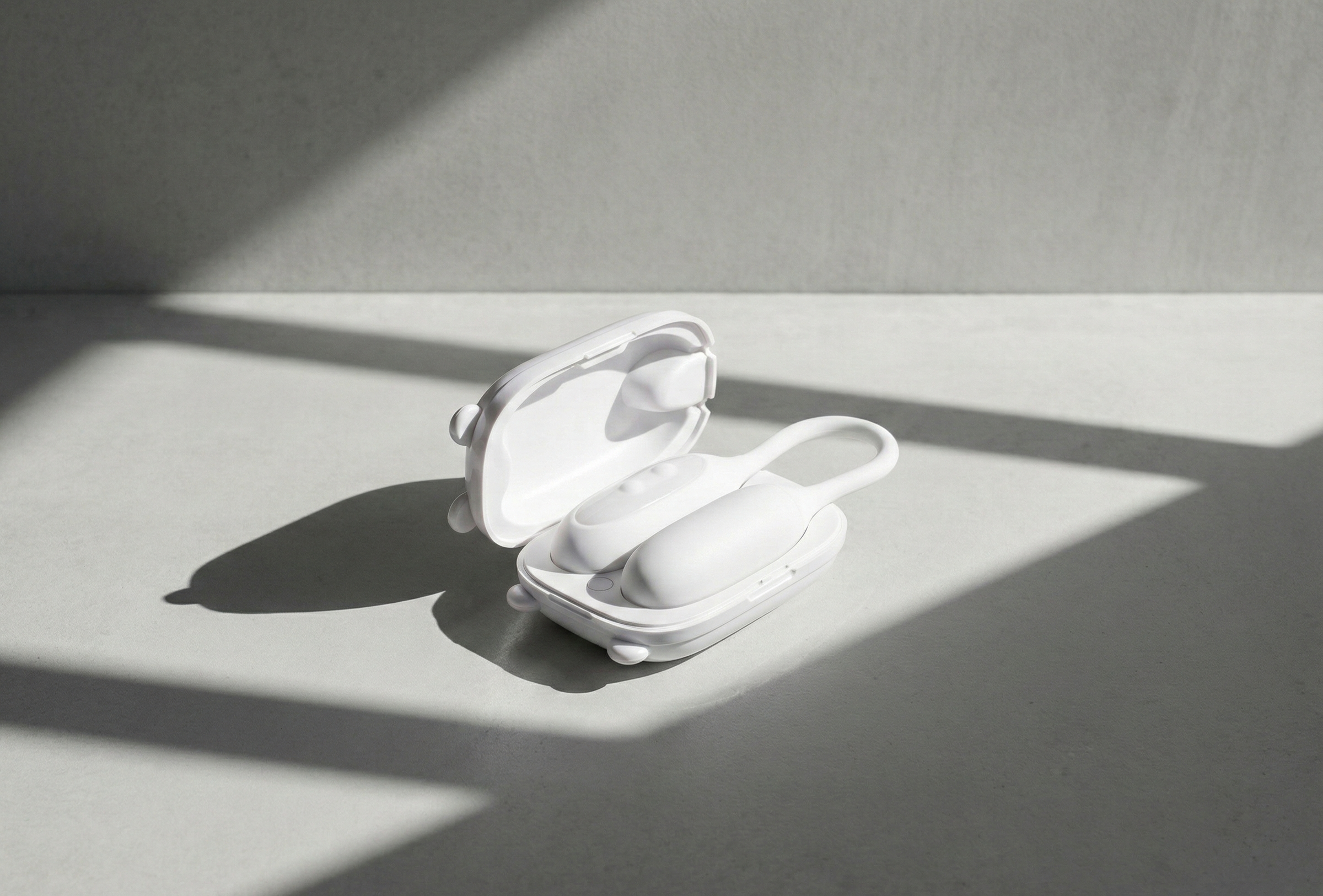 White wireless vibrator in a charging case on a light gray surface with soft shadows.