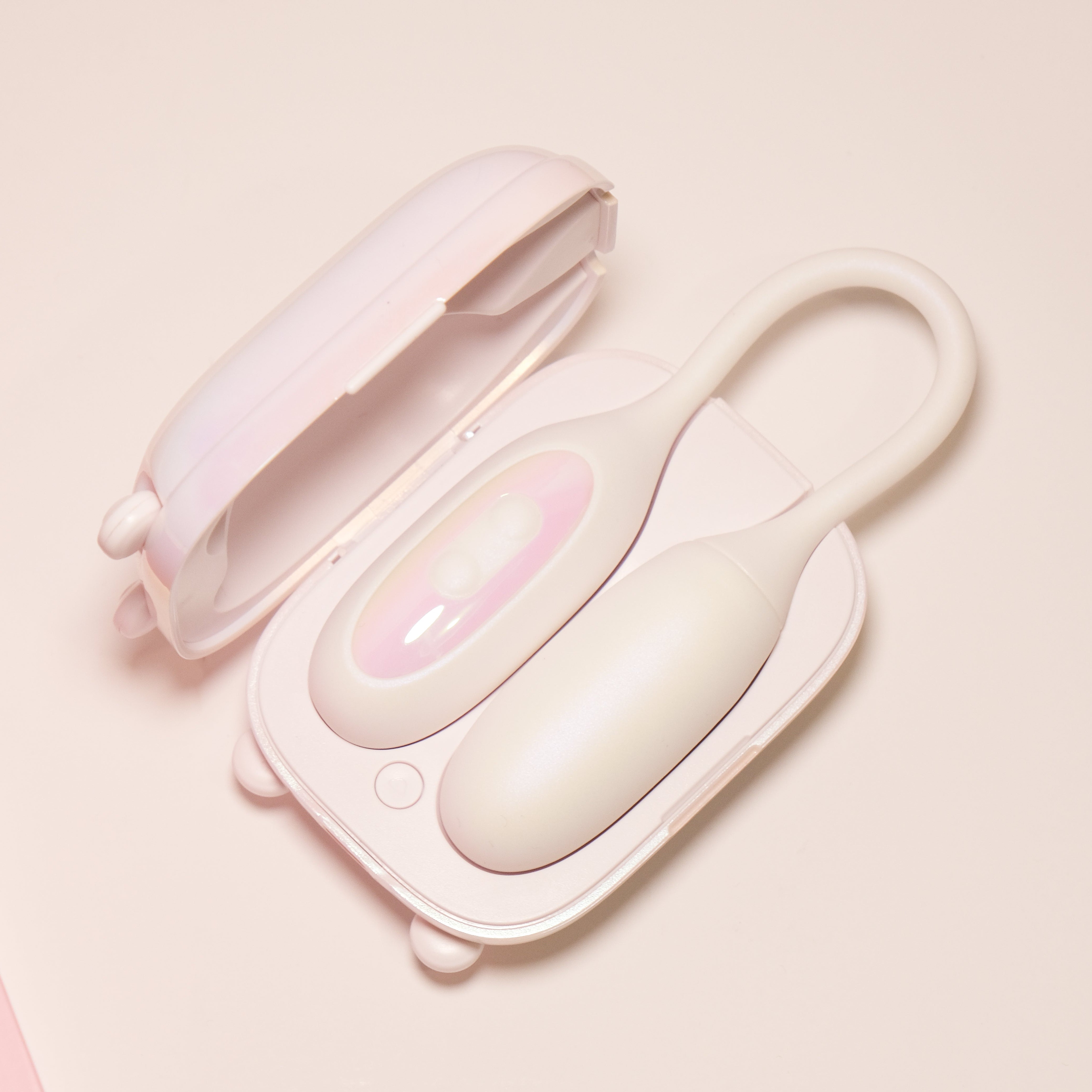 Aesthetic pastel NOX Traveller charging case open, displaying the white beginner vibrator inside next to pink branded packaging.