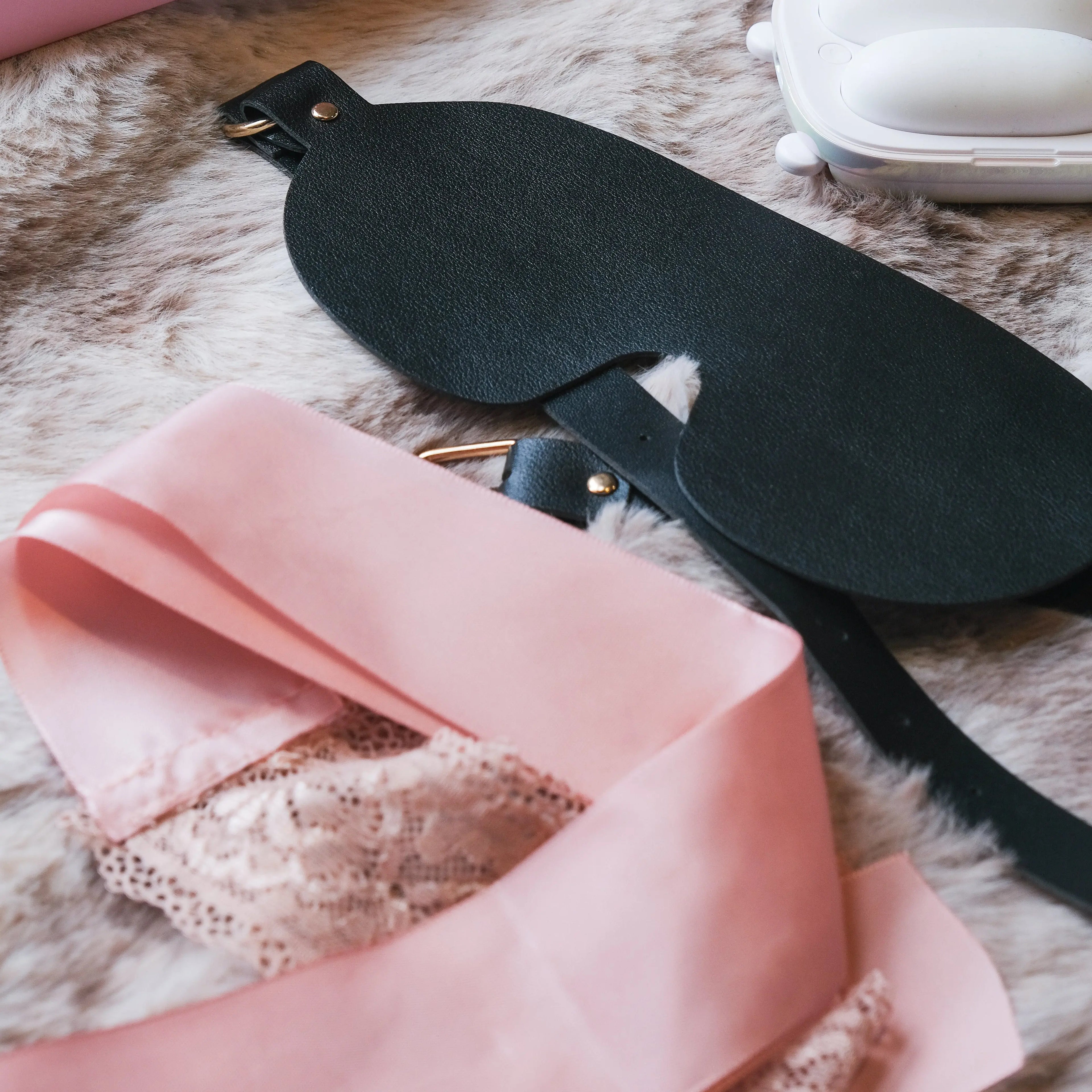 Detail shot of the premium black leather and pink silk blindfolds included in the NOX Traveller kit.