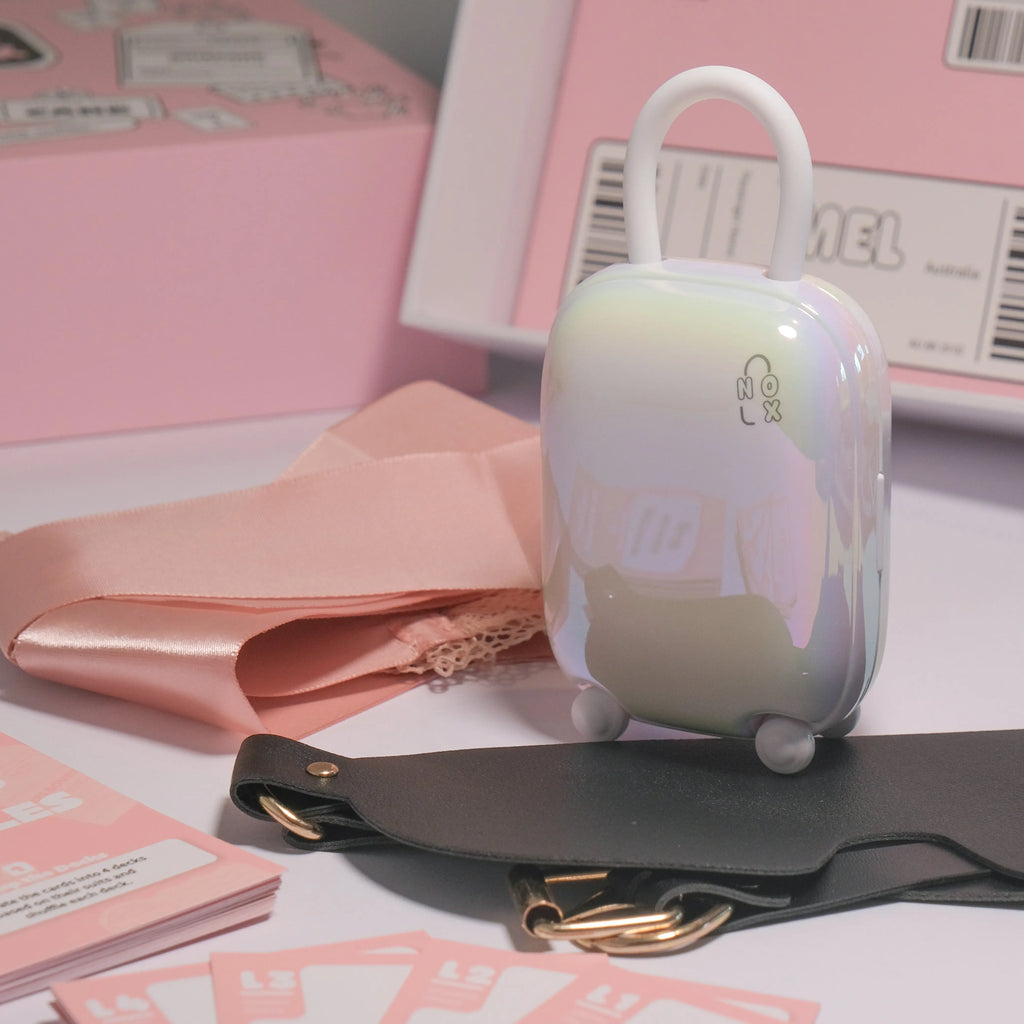 NOX Traveller suitcase charger standing next to a soft pink ribbon and black blindfold for sensory play.